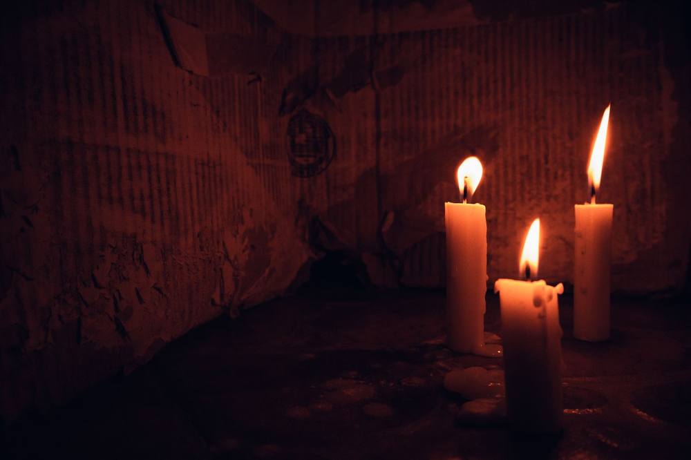 Three candles burning in a dark room